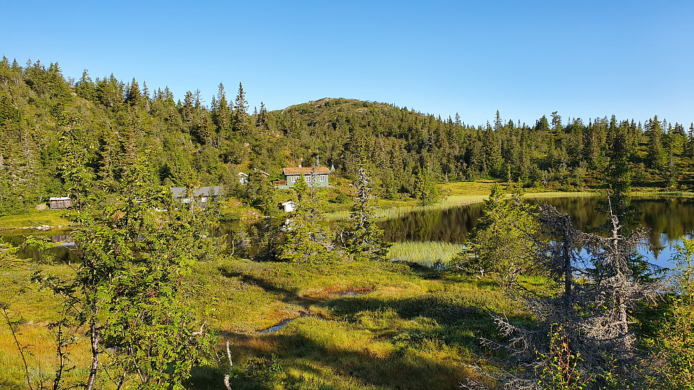 Opsal damtjønn med et par hytter som ligger på vestsiden av tjernet. Toppen bak midt i bildet, er Fjellstadfjellet (1035).