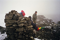 28.07.1996 - På toppen av Snøholstinden (2141), i frisk vind, tåke og snø/haggel. Vi var ganske raske med å kle på oss mer vinterlig tøy og komme oss ned i lavere lende. Sjelden har oppholdet på toppen vært så kort.