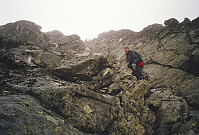 28.07.1996 - Vi er på vei ned det bratte punktet på sørryggen på Snøholstinden (2141), i rundt 2000 meters høyde. Det sluddet og var vått, så vi tok det veldig pent ned den bratte renna. Her er Johan Kristian på vei ned, mens Per Rune og Nils Brede ses øverst der de venter på tur.