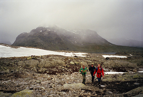 28.07.1996 - Mens snøbygene fortsetter å feie over Snøholstinden (2141) i bakgrunnen, vandrer vi tilbake mot Fondsbu.