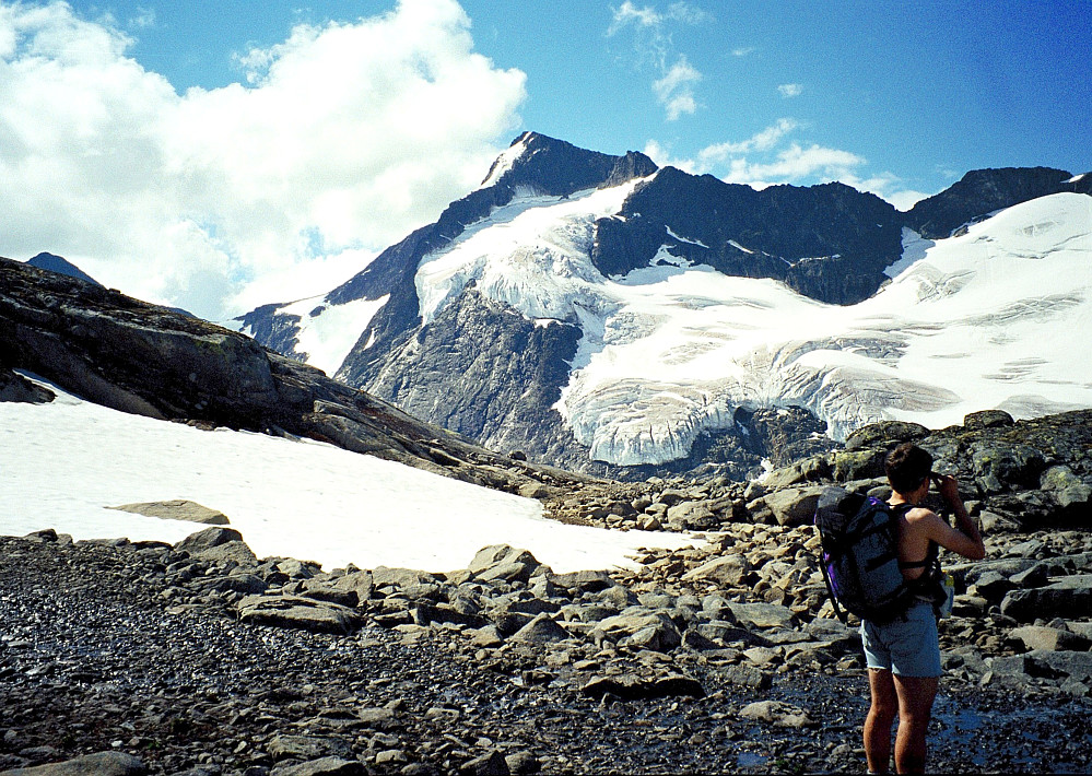 13.07.1997 - Kai Roger ved det lille vannet på rundt 1760 meters høyde, 500 m sørvest for Nørdre Skarvflytinden (2073). Bak ruver Store Knutsholstinden (2341) med de flotte hengebreene.