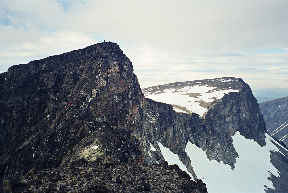 10.07.1999 - Bildet er tatt fra Storgrovtinden (2229). Litt til venstre er Bakarste Storgrovhøe (2259), hvor Grete ses på toppen med armene i været. Hans Petter lyser opp med rød jakke lenger nede på ryggen, hvor han står og venter på nordsiden av hakket som må klatres. Til høyre i bildet er Fremste Storgrovhøe (2253).