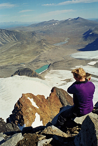 04.09.1999 - Hans Petter på kanten av øststupet på Leirhøe (2330). Langt under oss lyser Veobreahesten (2185) opp med sitt røde berg.