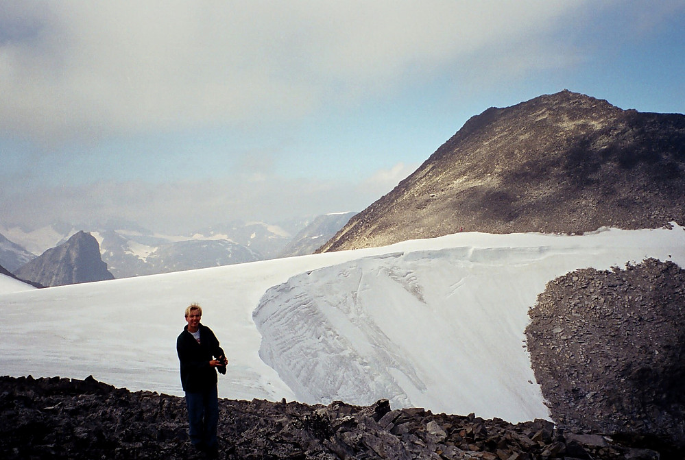 11.09.1999 - Vi er ved Urdadalstinden SV0 (2061). Bak meg ses Visbrean, og oppe til høyre er Semelholstinden (2147). Vi krysset over breen med en del meters margin til den bratte nordøstskråningen, hvor det stuper ned i Semelholet. To personer kan ses ute på breen, ganske nøyaktig midt i bildet.