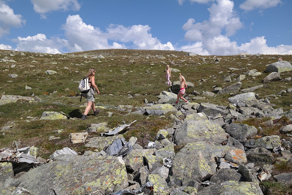 22.07.2014 - Vrakdeler etter flyet ligger strødd blant steinene. Her dukker toppkrona på Borgsjåbrotet (1485) opp i bakgrunnen.