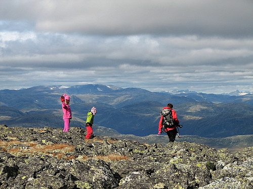 På toppen av Fossebrea (1664). Over jentene ses Høgeloft (1920), mens Jotun-topper stikker opp langt der bak til høyre. Bl.a. ses Uranostinden (2157) helt til høyre.