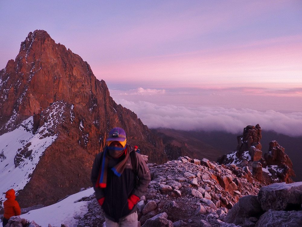 Our local guide John, on the final slopes to the top of Poin  Lenana, with the huge rock face of Batian behind