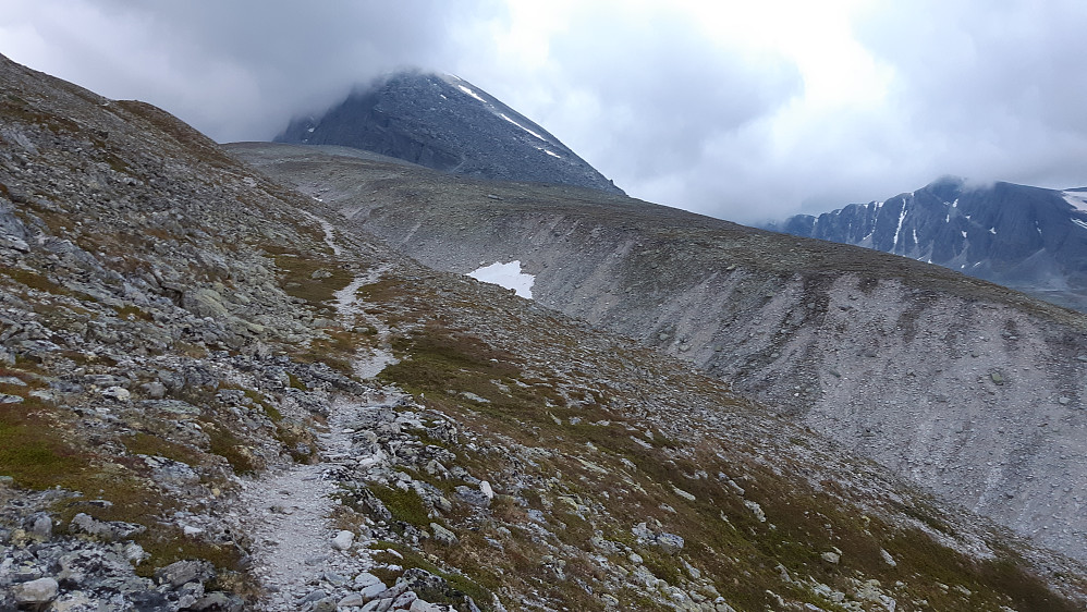 Trolltinden med tåke. Ruta ned på nordsiden er brutal med store blokker som kan være slitsomme å forsere. Bildet viser stien øverst i dalen, der den har svingt av fra Dørålen i retning Langholvatnet. 