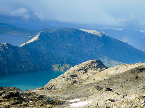 Utsikt mot Veslløyfttinden, Gjende, Besseggen og Bessvatnet. Merk den lille regnbuen på stien ned fra Besseggen.