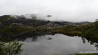 Det tilslørte Røyrfjellet speiler seg i Fagerdalstjørna.