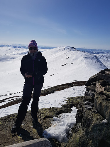 Trine på toppen med toppe  Sørvest for Storskarven i bakgrunnen. Nydelig vær, men litt vind akkurat på toppen.